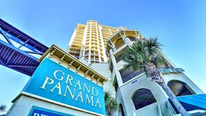 Un hotel chiamato Grand Panama con un cartello ben visibile, un edificio alto sullo sfondo e una palma in primo piano.