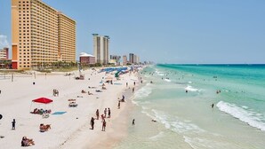 Una spiaggia con una fila di alberghi alti, acqua cristallina color turchese e persone che si godono la spiaggia.