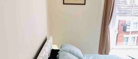 Un dormitorio con cama, una lámpara de noche y un cuadro en la pared.