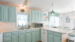 A kitchen with teal cabinets, a microwave, and a sink. - Direct Bay front home with 2 community pools and tennis (Ocean City)