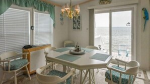 A room with a dining table, chairs, a chandelier, a view of the sea, and a parrot decoration. - Direct Bay front home with 2 community pools and tennis (Ocean City)