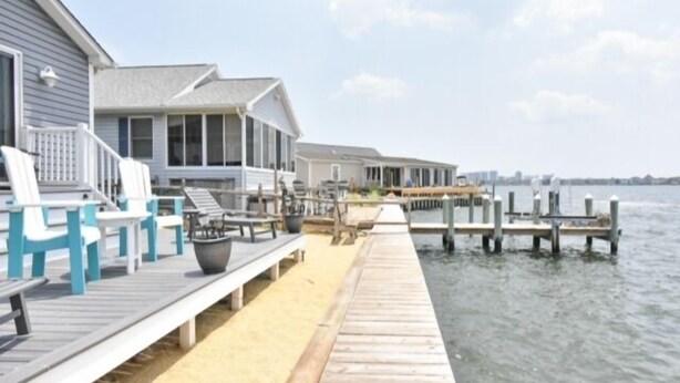 A waterfront property with a wooden dock leading to a house with a covered porch. - Direct Bay front home with 2 community pools and tennis (Ocean City)