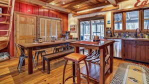 A cozy cabin-style kitchen with wooden beams, a large dining table, and bar stools. - This completely renovated Canaan Valley chalet offers it all, and more! (Canaan Valley)