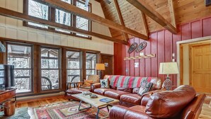 A cozy cabin interior with a leather sofa, a patterned rug, and a wooden ceiling. - This completely renovated Canaan Valley chalet offers it all, and more! (Canaan Valley)