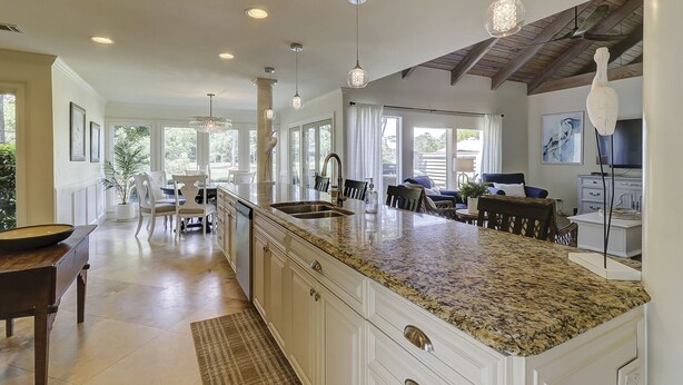 A spacious kitchen with a large island, pendant lighting, and a view to the outdoors.
