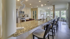 A spacious kitchen with a granite countertop, stainless steel appliances, and pendant lighting.