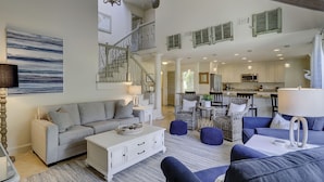 A spacious living area with a staircase, a kitchen, and a dining area.