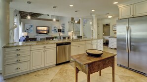 A spacious kitchen with white cabinetry, a stainless steel refrigerator, and a granite countertop.