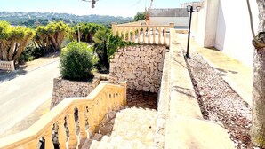 A stone staircase leading to a balcony with a view of a cityscape and a clear sky.