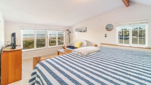 A bedroom with a large bed, a desk with a computer, and a view of the beach through two windows. - Beachfront! Walk the short path to the Beach, or enjoy the waves from the Deck (Rockaway Beach)
