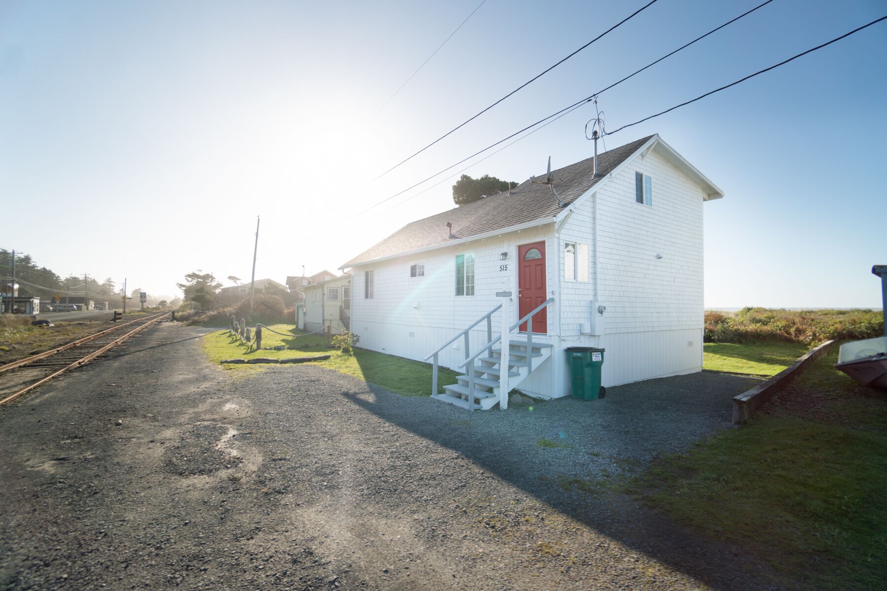 A small white building with a red door and a staircase leading up to it.