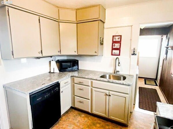 A compact kitchen with a dishwasher, a microwave, and a sink.