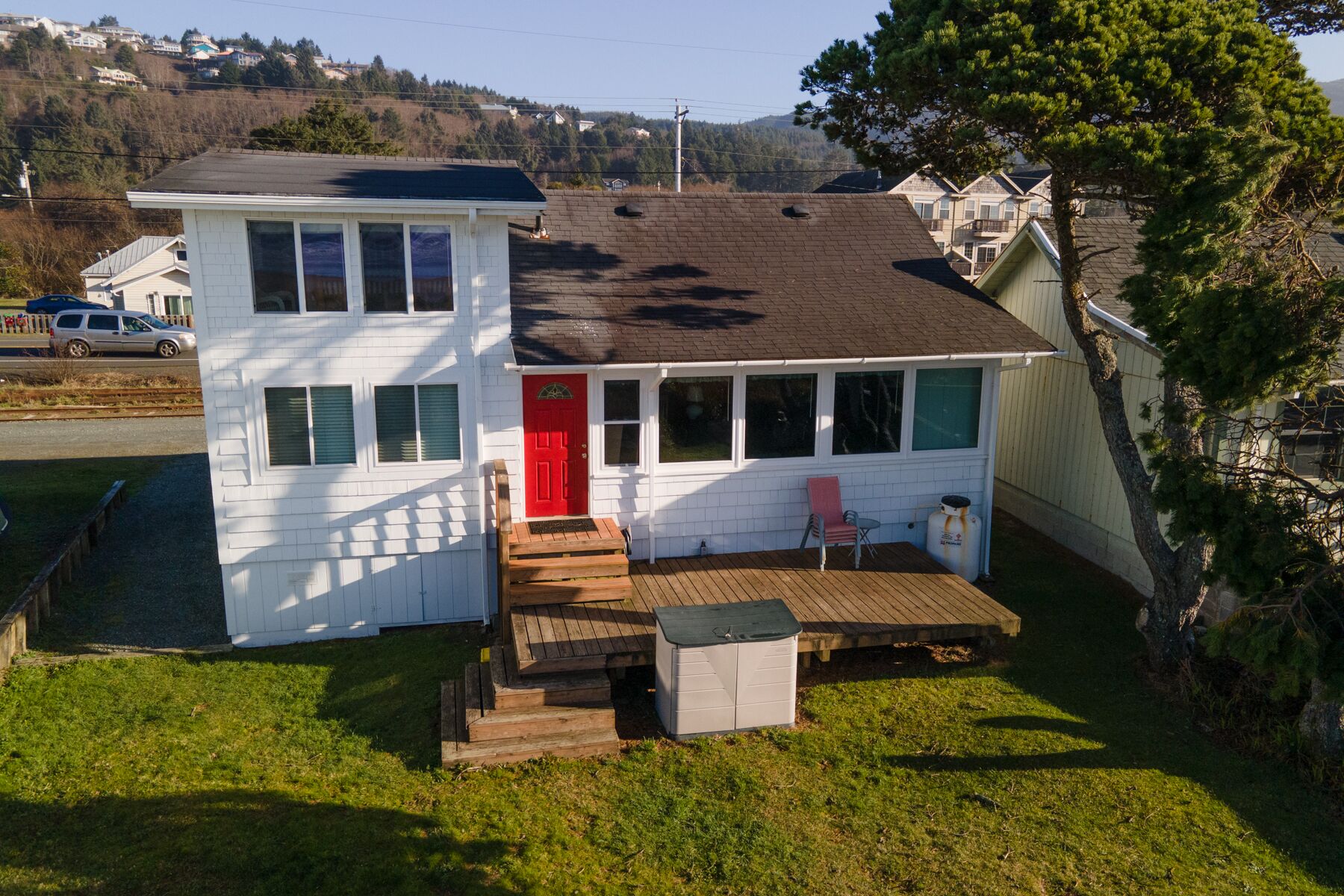 Ein zweistöckiges Haus mit roter Tür, einer kleinen Veranda und einer Garage.