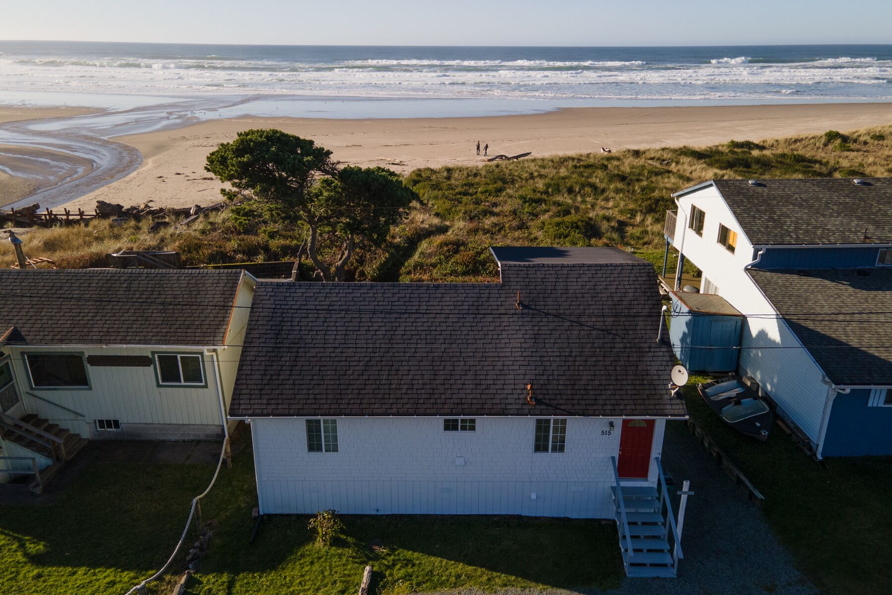 A coastal property with a white house, a garage, and a beach view.