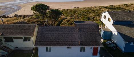 A coastal property with a white house, a garage, and a beach view.
