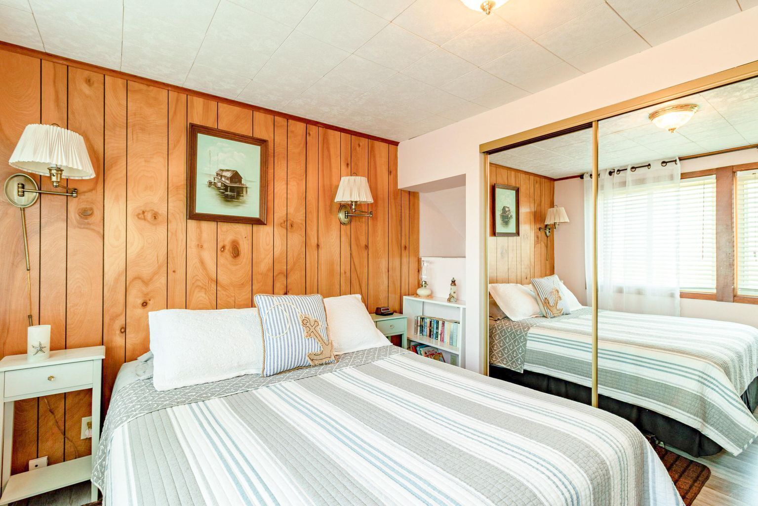 Une chambre confortable avec deux lits, des lambris en bois, un grand miroir, des lampes de chevet et une petite bibliothèque.