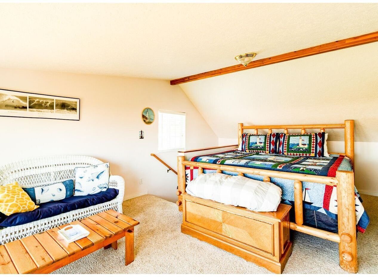 Une chambre confortable avec un lit en bois, un canapé en osier blanc et une table basse en bois.
