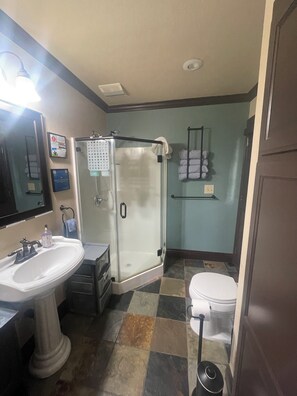 A bathroom with a pedestal sink, a glass-enclosed shower, a toilet, and a towel rack with towels. - Rancho's Private Oasis (Rancho Cucamonga)