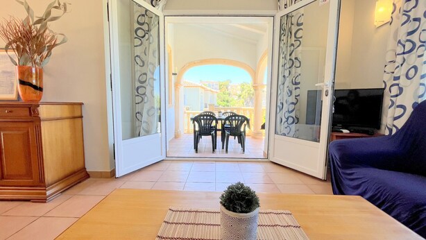 A living room with a sofa, a coffee table with a plant, and a TV on a stand. - 0361 Villa Monte Javea Laurel (Javea / Xàbia)