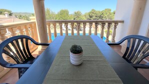 A balcony with a table and chairs, a potted plant, and a view of a swimming pool and greenery. - 0361 Villa Monte Javea Laurel (Javea / Xàbia)