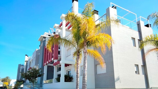 Un bâtiment moderne à la façade blanche, agrémenté de touches de rouge et doté d’une pelouse bien entretenue.