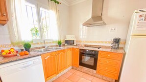 Eine Küche mit Holzausstattung, einem Geschirrspüler, einem Backofen und einem Kühlschrank.