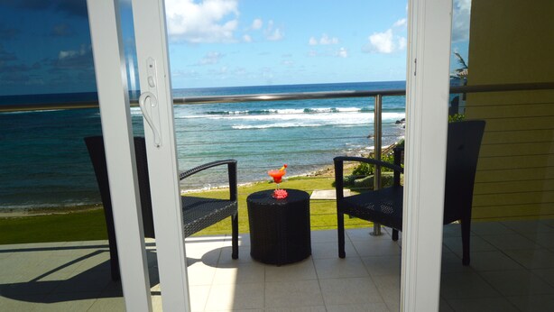 A balcony with a view of the ocean, a small round table with a red object, and two chairs. - Building A- Condo - Direct Ocean Front Views...directly on the beach. (Sint Maarten)