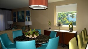 A dining area with a round table, blue and yellow chairs, a decorative centerpiece, and a view of a tropical landscape through a window. - Building A- Condo - Direct Ocean Front Views...directly on the beach. (Sint Maarten)