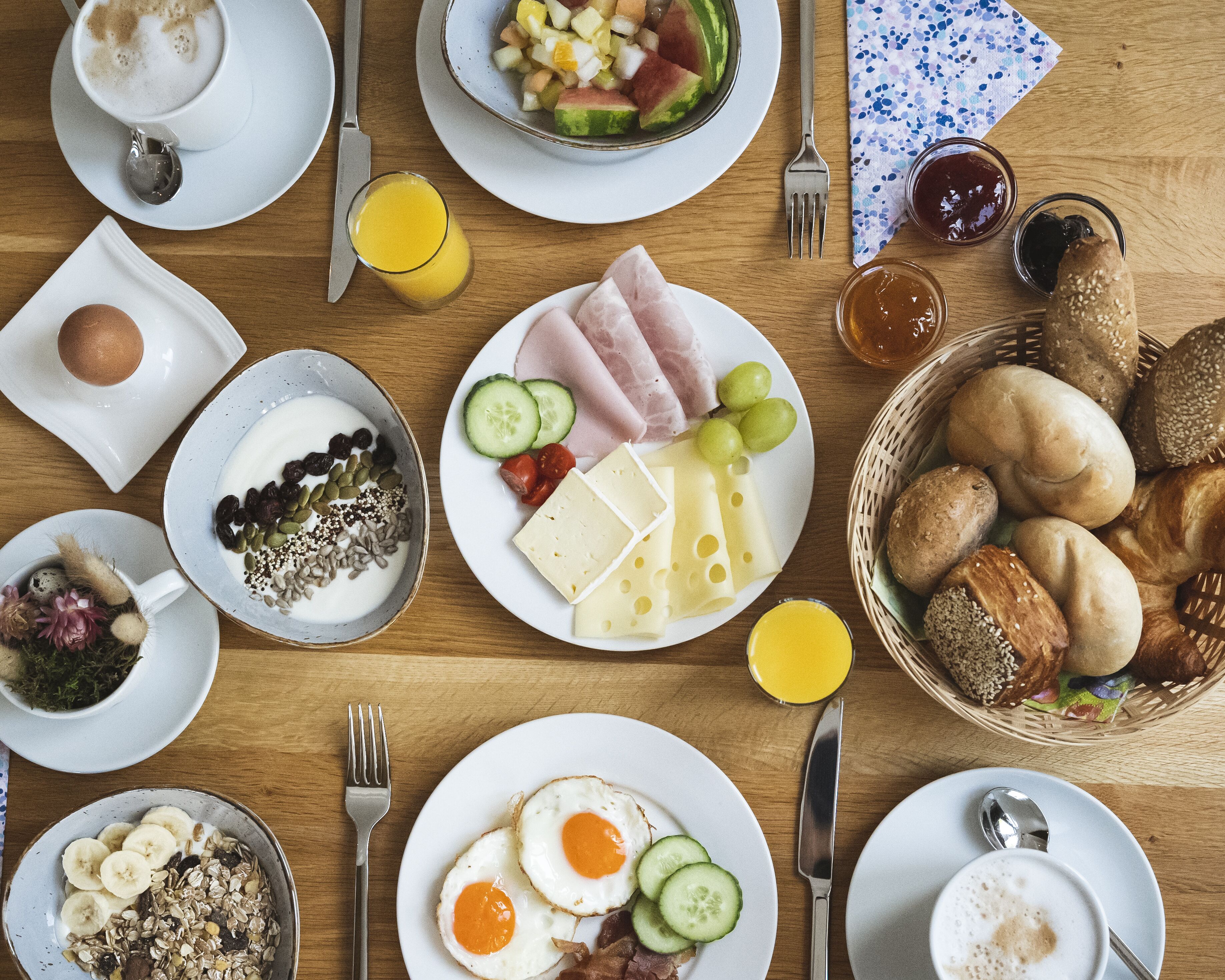 Une table de petit-déjeuner avec divers aliments, notamment des œufs, du fromage, du pain et des fruits.