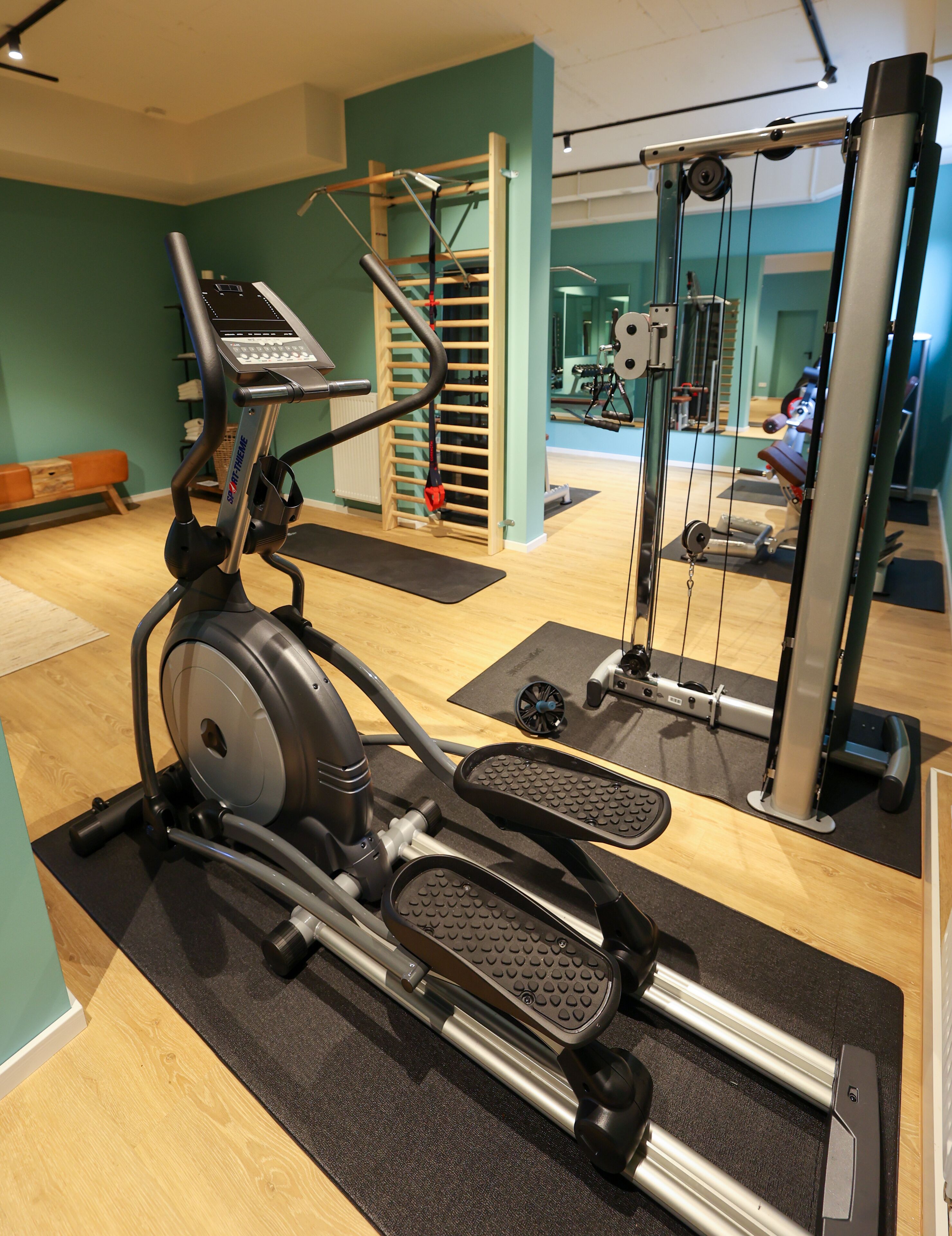 Un gimnasio con una máquina elíptica, una cinta de correr y una máquina de pesas.