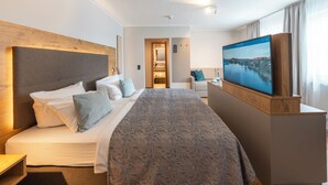 Habitación de hotel con una cama grande, televisión, cabecera de madera y vista a un paisaje urbano.