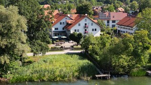Un hotel junto al lago con varias edificaciones, mesas al aire libre y un muelle.