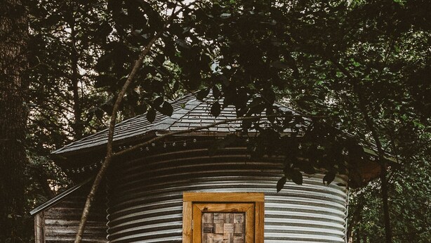 Un chalet rustique avec une porte en bois et une fenêtre ornée d’un motif en chevrons.