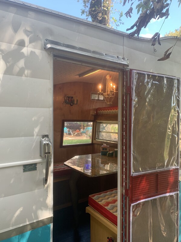 A compact RV interior with a kitchenette, a dining area, and a small seating space.