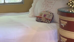 Un intérieur chaleureux avec un lit, un coussin décoratif, une lampe et une fenêtre.