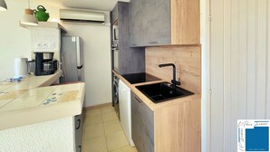 A compact kitchen with a built-in microwave, a coffee maker, and a sink.