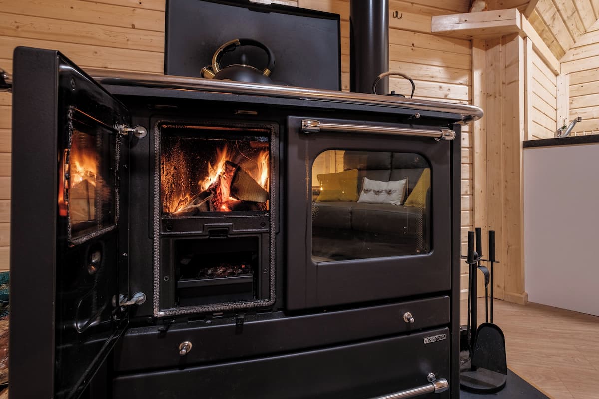 Un poêle à bois à porte ouverte, laissant apparaître le feu à l’intérieur.