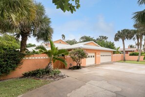 A residential house with a garage, surrounded by palm trees and a well-maintained lawn. - Beachside OASIS - Private Pool - Steps to private beach & restaurants (Melbourne Beach)