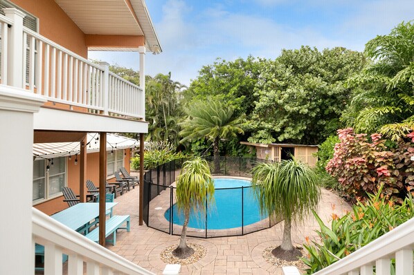 A backyard with a swimming pool, outdoor seating, and lush greenery. - Beachside OASIS - Private Pool - Steps to private beach & restaurants (Melbourne Beach)