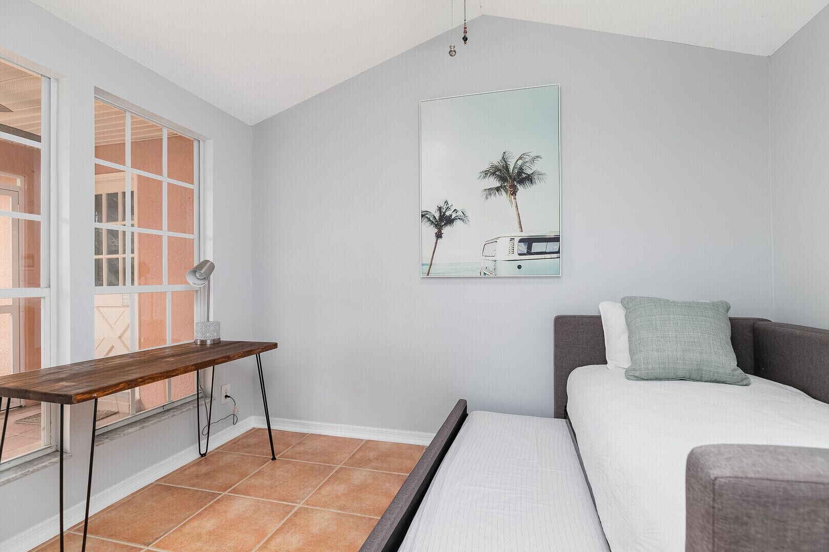 A bedroom with a bed, a desk, and a window.