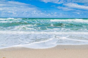 A beach with waves crashing onto the shore under a clear sky.