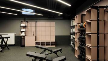 Un gimnasio con equipo de ejercicio, bancos y estantes para pesas.