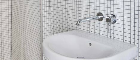 Ein Badezimmer mit Waschbecken, einer chromfarbenen Armatur und Fliesenwänden.