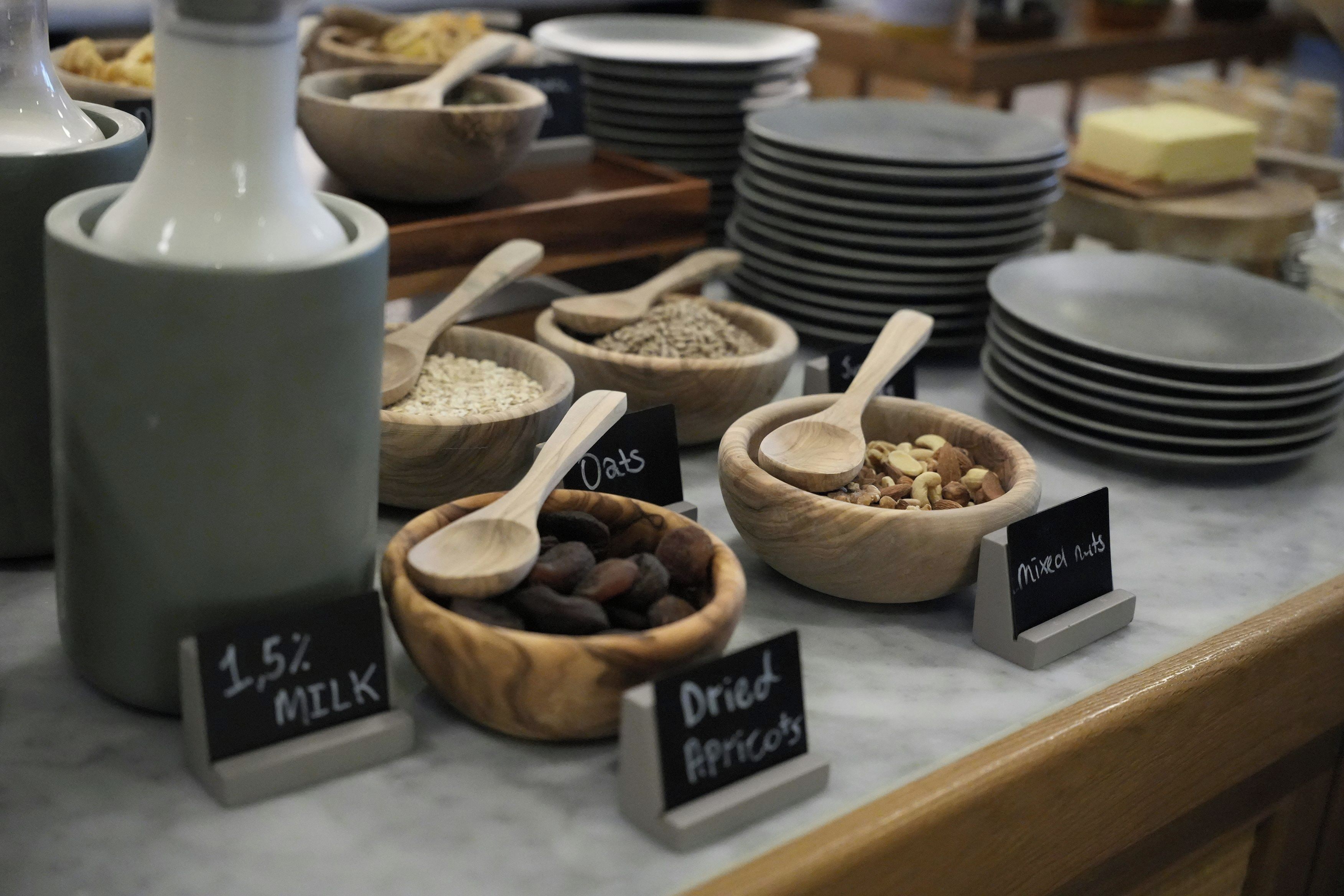 A food display with labeled containers of dried apricots, oats, and milk.
