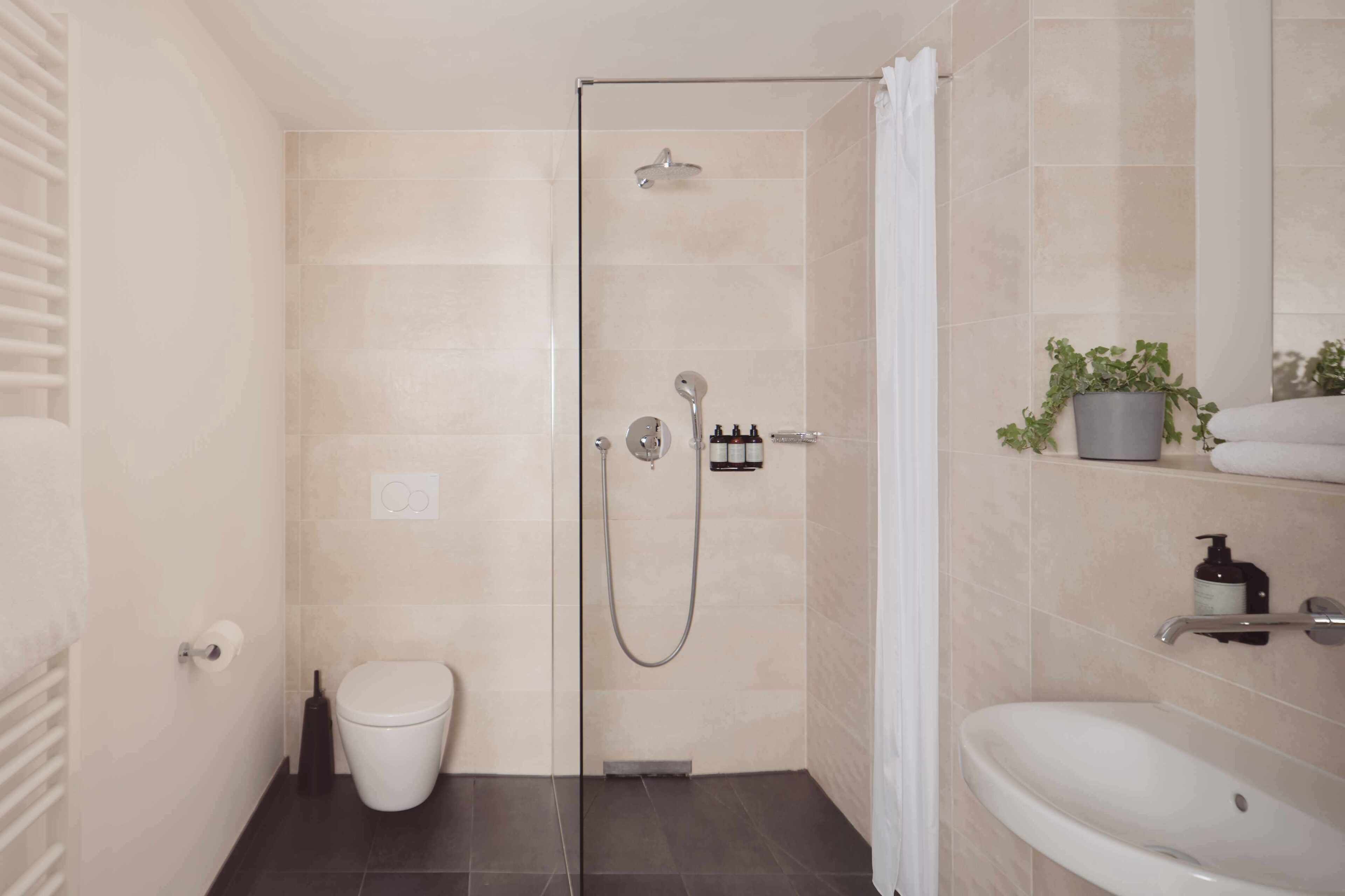 A modern bathroom with a shower, toilet, and sink.