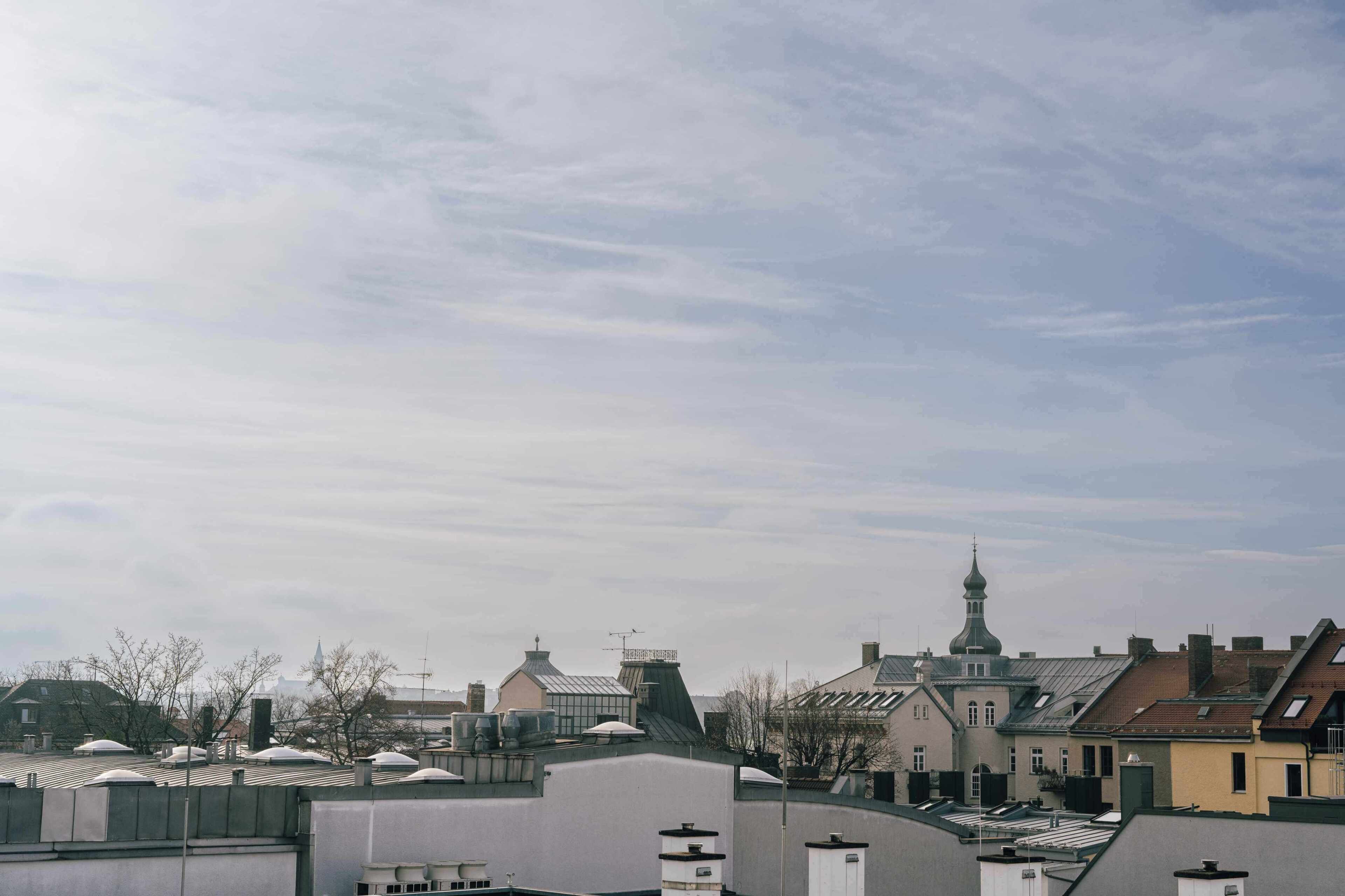 A cityscape with multiple buildings, including a church with a tall spire, and a variety of rooftops.
