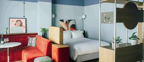 Un dormitorio moderno con una cama litera, un sofá rojo, una mesa redonda y una lámpara colgante.