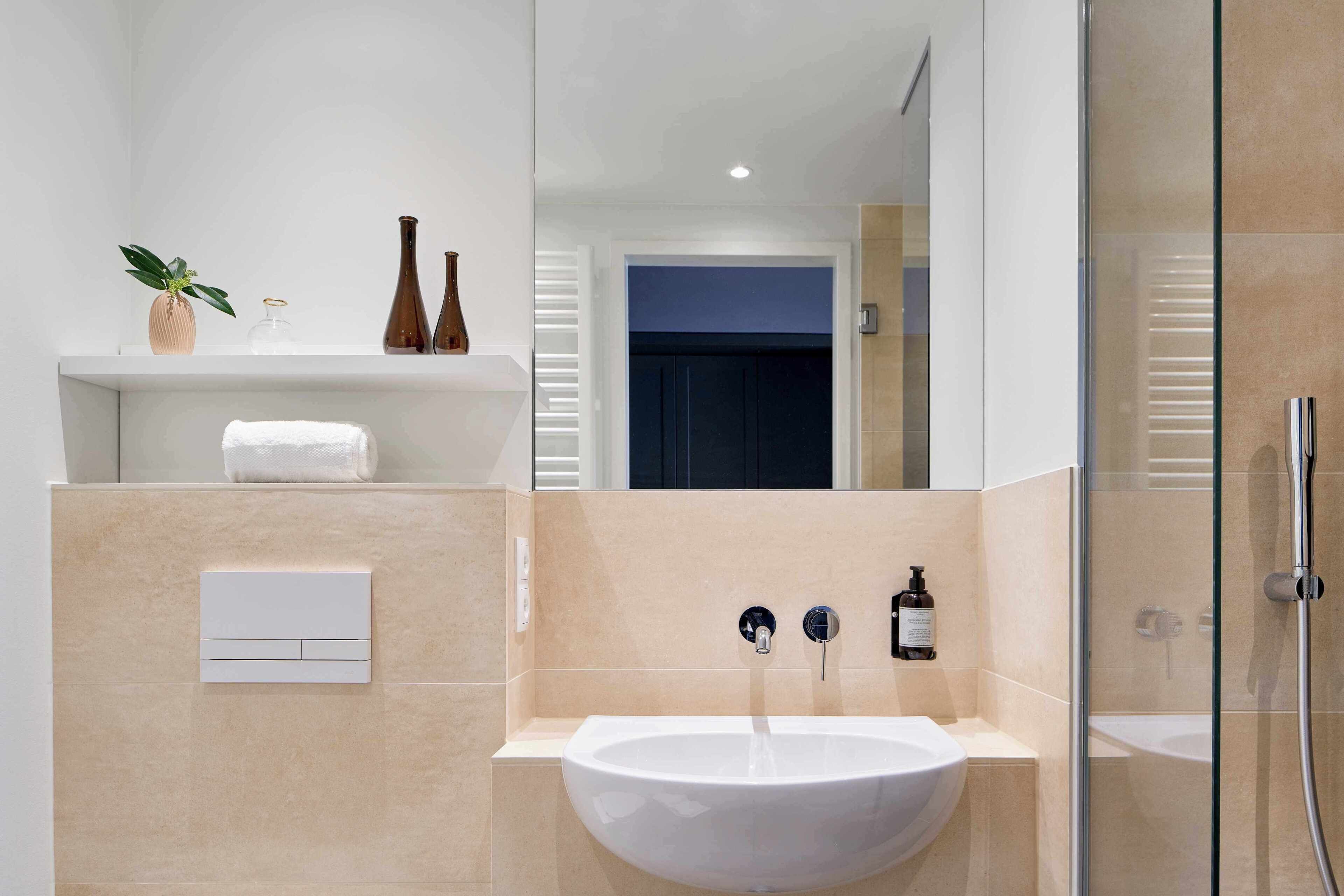 A modern bathroom with a white sink, a mirror, a towel, and a shower.