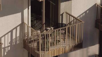A balcony with a metal railing, a chair, and a table.