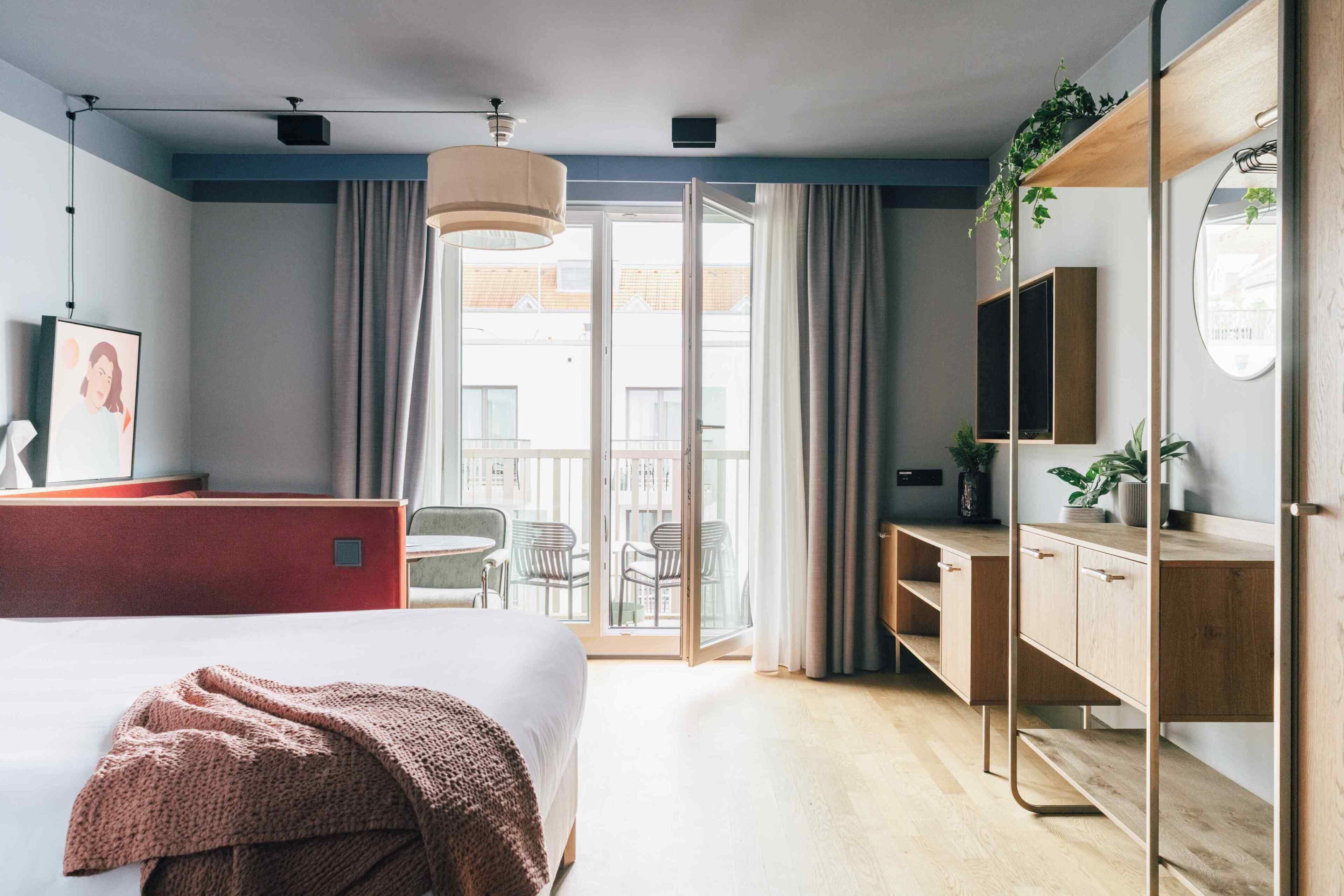 Ein Hotelzimmer mit Bett, Schreibtisch, Fernseher und einem Balkon mit Blick.